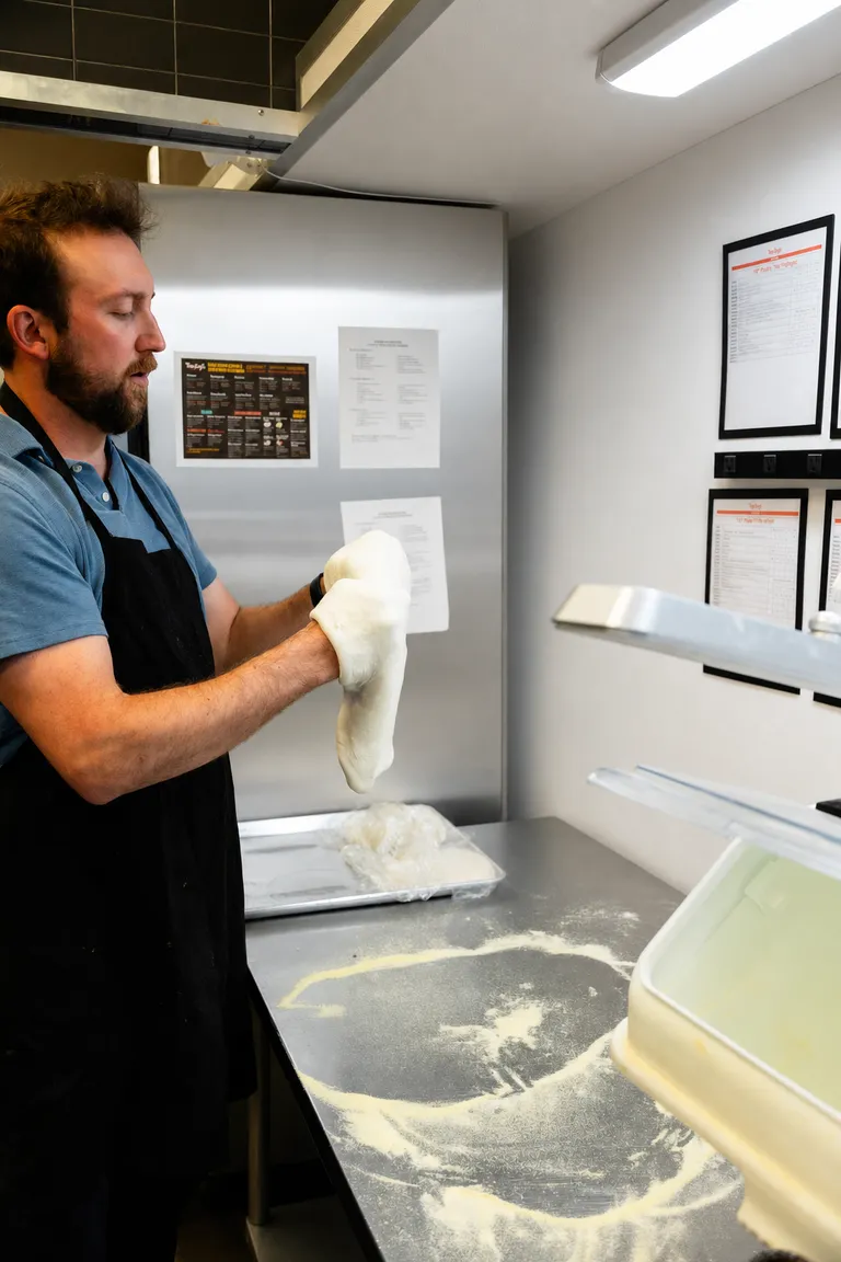 Stretching pizza dough over knuckles