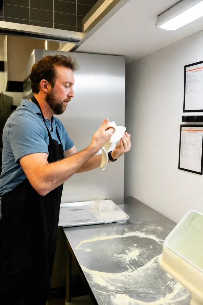 Folding pizza dough in the prep kitchen