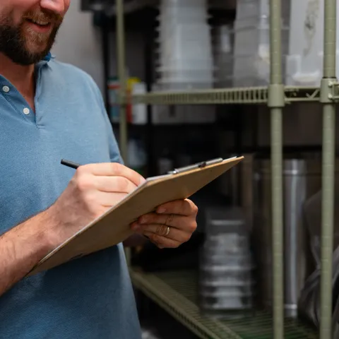 Taking inventory notes on a clipboard in a dry storage room