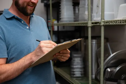 Taking inventory notes on a clipboard in a dry storage room