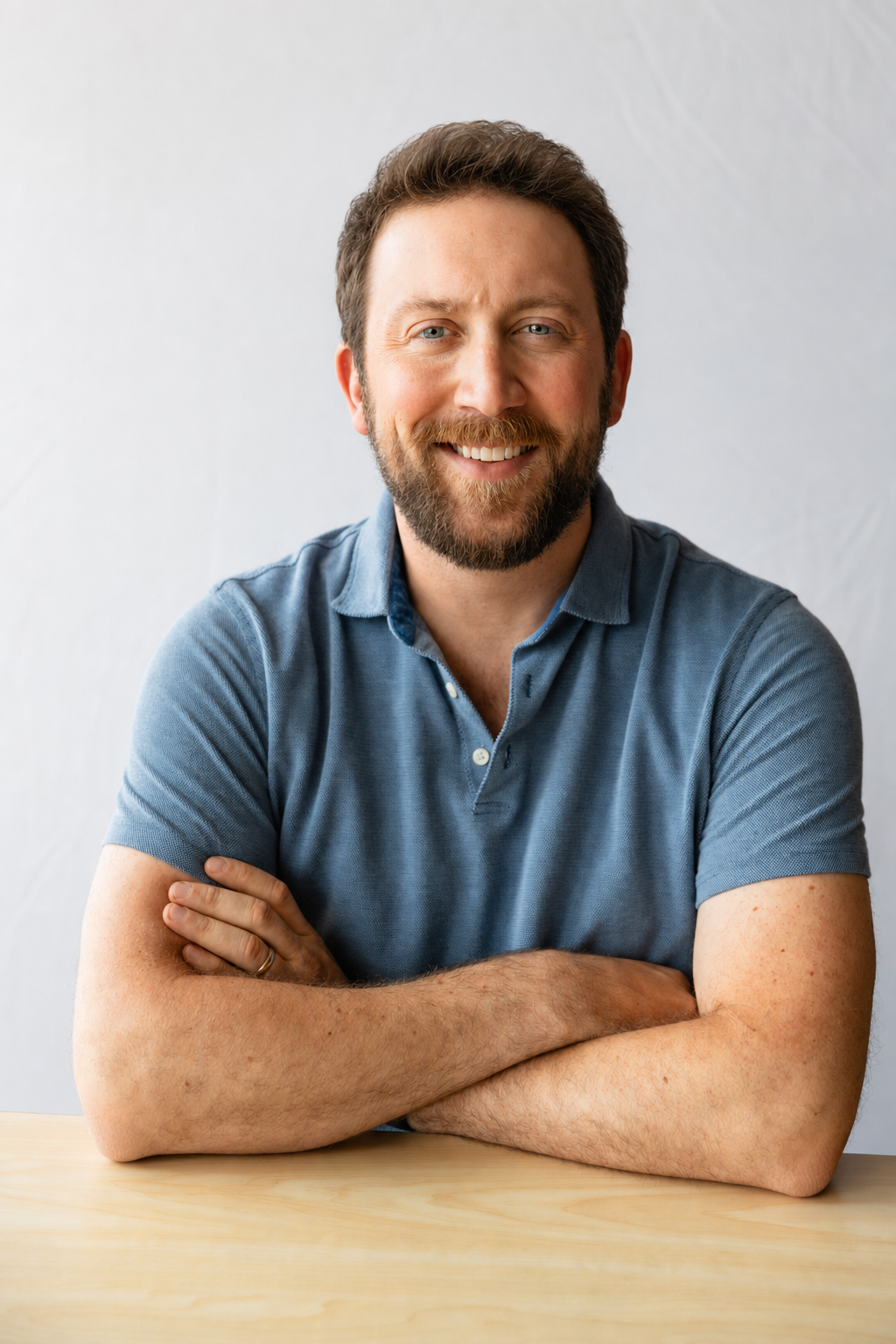 George Gilliam smiling with arms crossed at a wood table