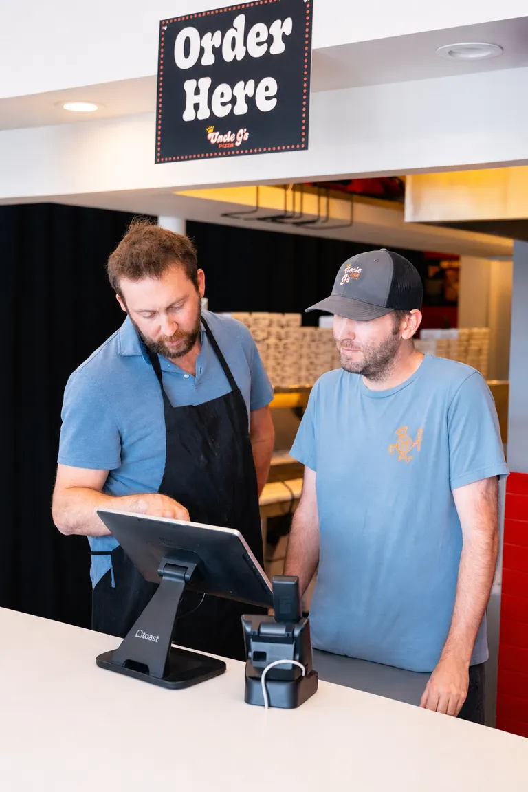 George pointing at a Toast POS screen while walking a teammate through it