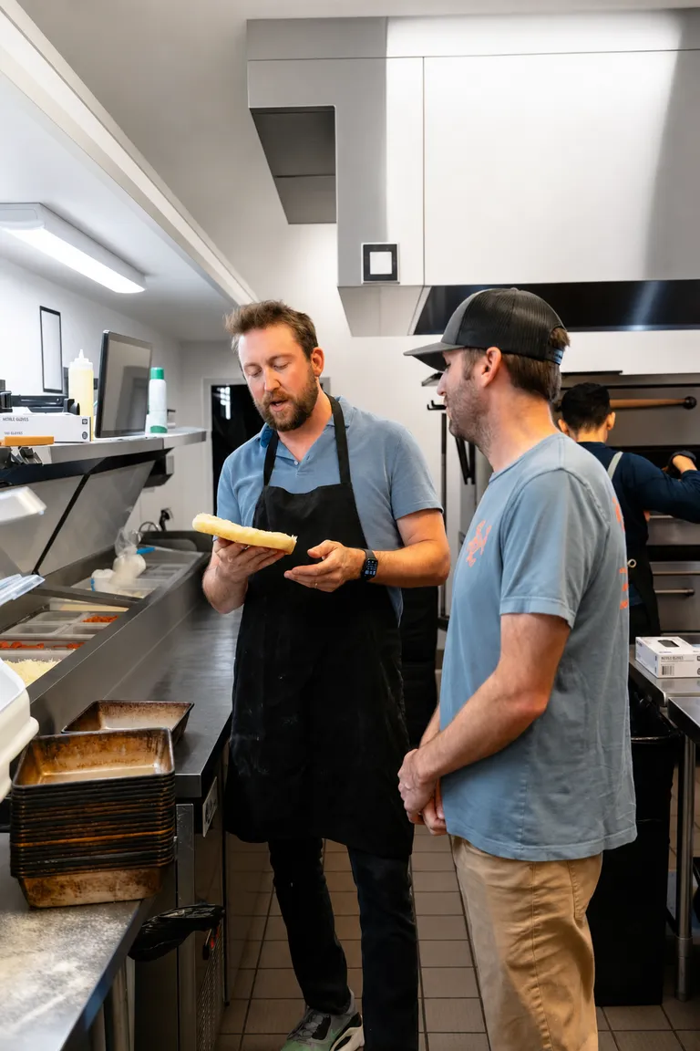 George talking through a recipe with a teammate on the kitchen line