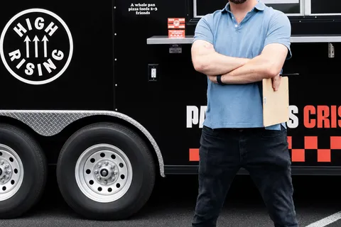 George standing beside the Uncle G's trailer with a clipboard under his arm