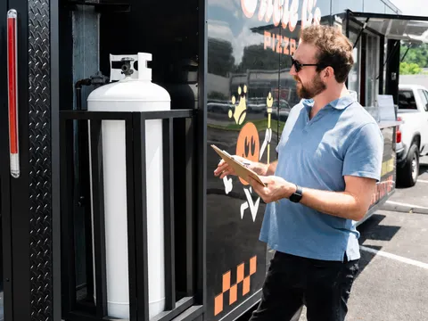 George reviewing the propane bay of a food trailer with a clipboard