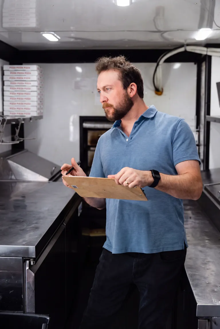 George inspecting the inside of the food trailer with a clipboard