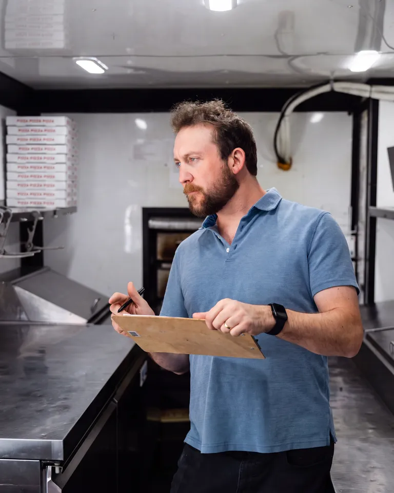 George inspecting the inside of the food trailer with a clipboard